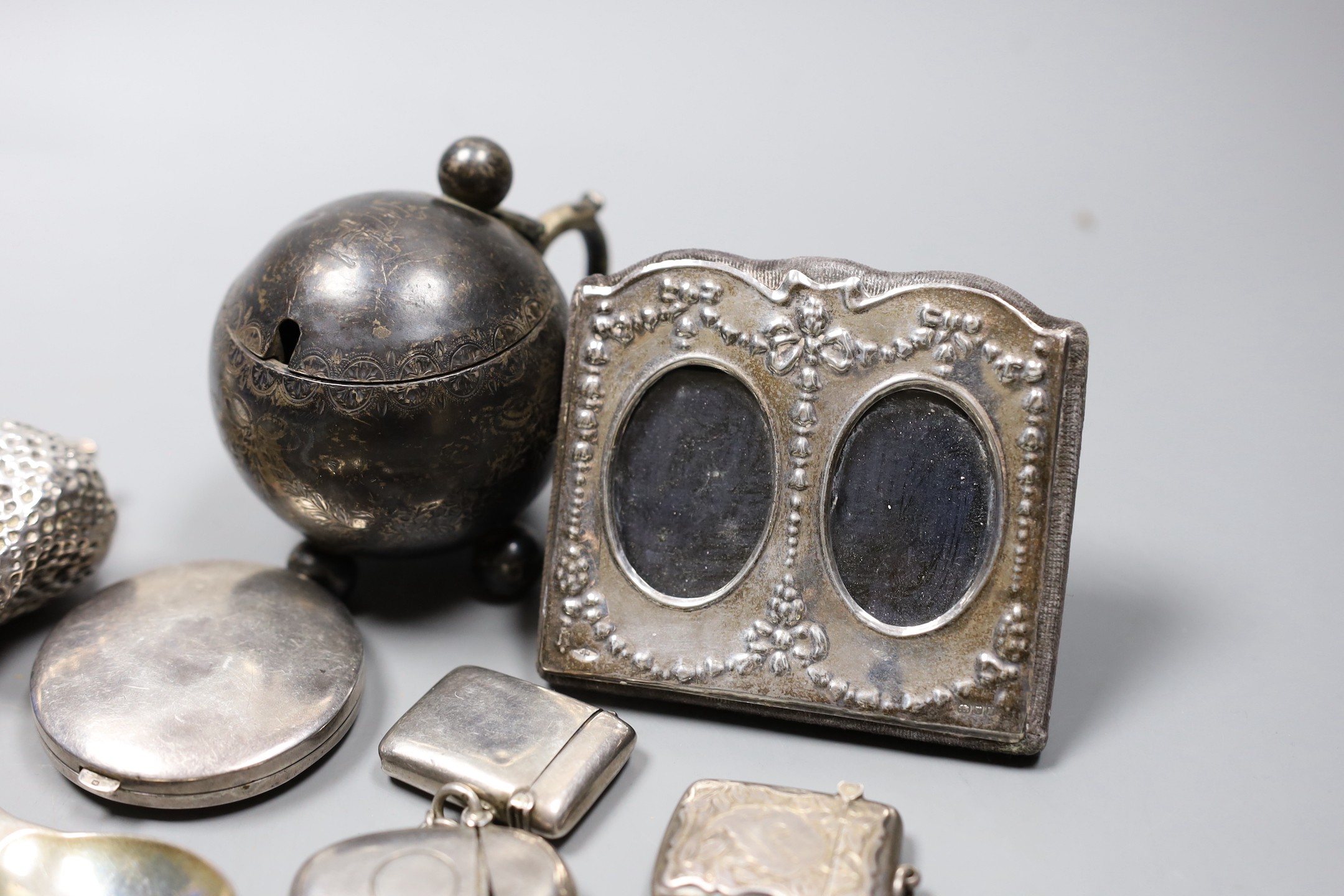 Sundry small silver including a Victorian globular mustard pot, two mounted photograph frames, three vesta cases, a caddy spoon, compact, circular white metal box and cover and a filled 'pair of strawberries' paperweight